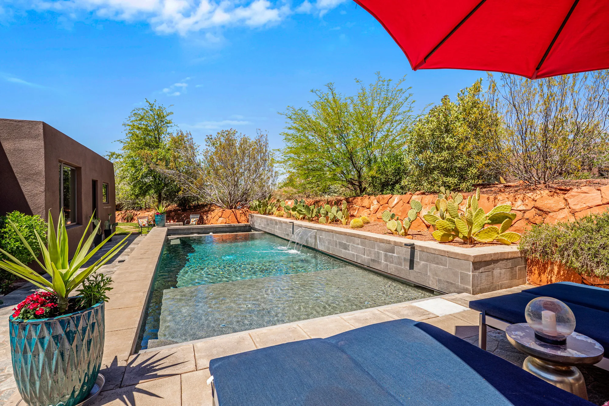 Outdoor swimming pool featuring a water feature, surrounding patio, and desert landscaping