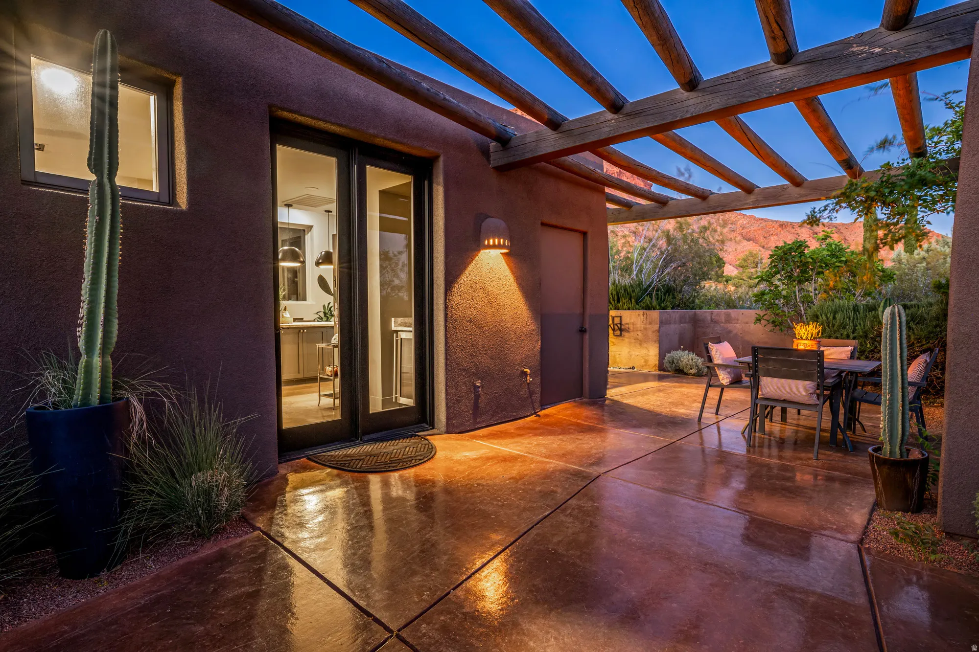 Spacious outdoor patio featuring a wood-beam pergola, durable concrete flooring, and a stone retaining wall