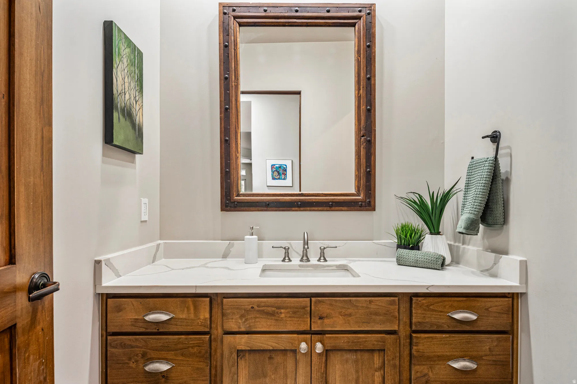 Bathroom vanity featuring a rectangular undermount sink, a stone-finish countertop with veining, wood cabinetry, and a framed mirror