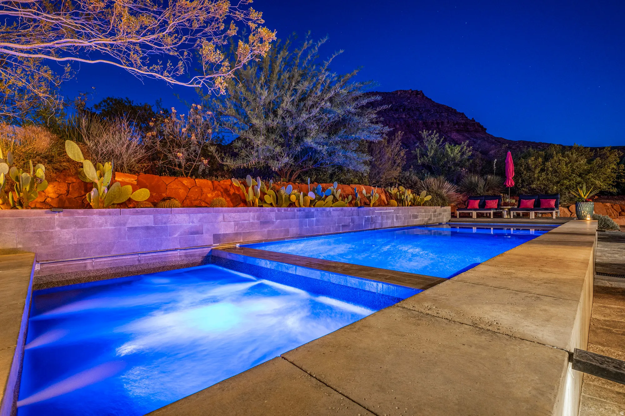 Multi-level water feature with integrated pool, spa, and tiered stone hardscaping