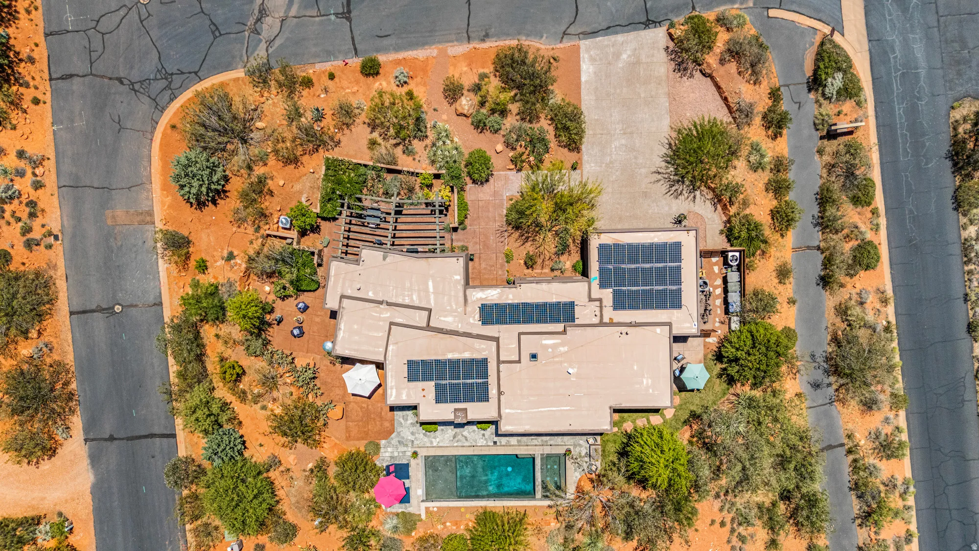 Contemporary residence with multiple rooflines, extensive solar panel arrays, a rectangular swimming pool, and a multi-level patio area