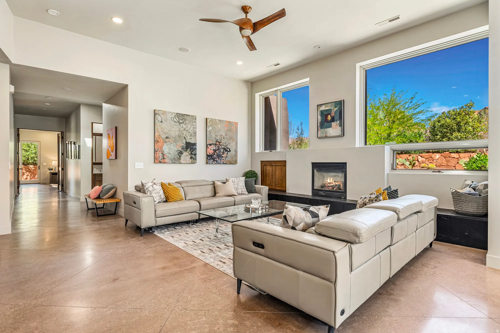 Spacious living area featuring high ceilings, large floor-to-ceiling windows, a built-in fireplace, and polished concrete flooring