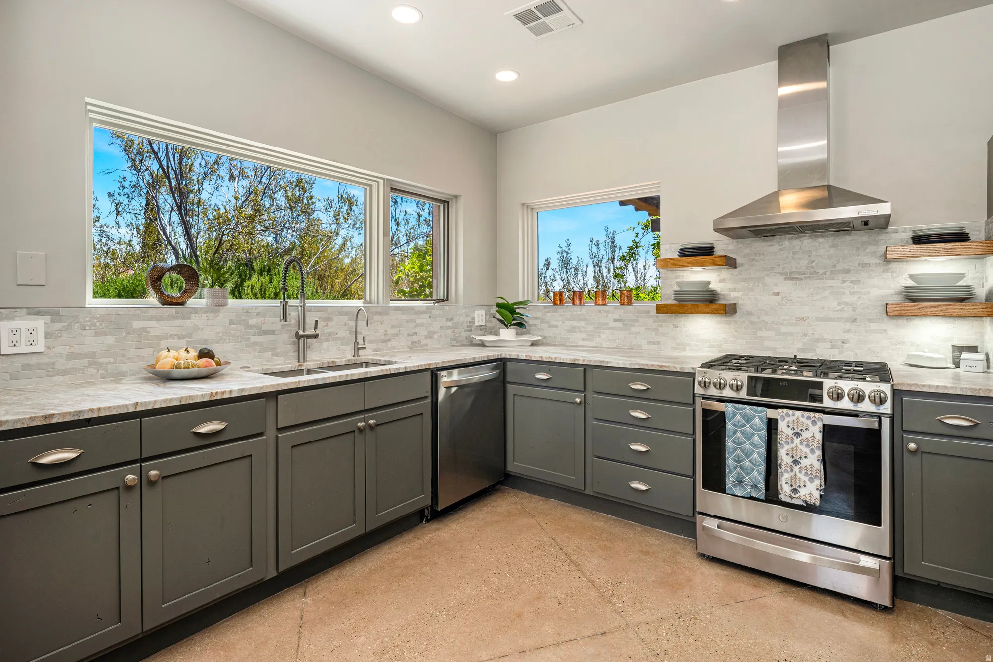 Kitchen featuring gray cabinetry, light-toned stone countertops, and a full tile backsplash
