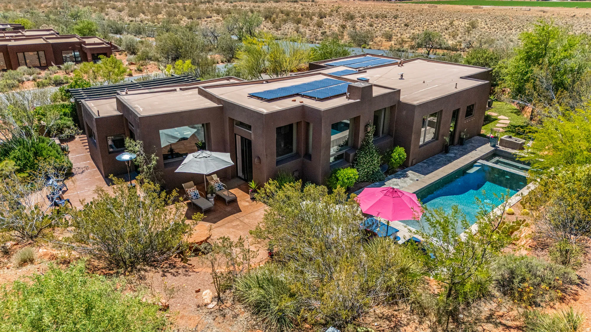 Modern stucco exterior with a flat roof, featuring multiple solar panels and large windows