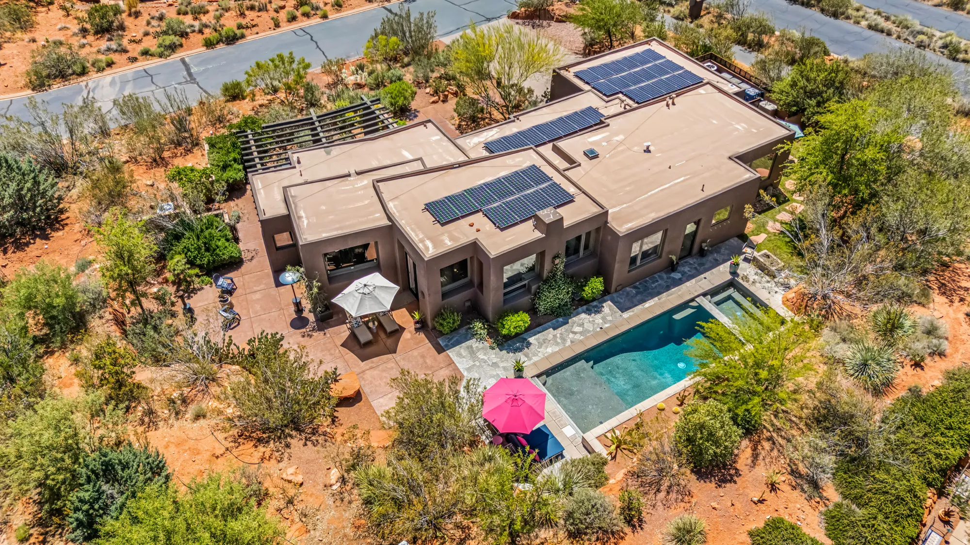 Contemporary architecture with a flat roof, integrated solar panels, a rectangular swimming pool, and an adjacent patio with a pergola