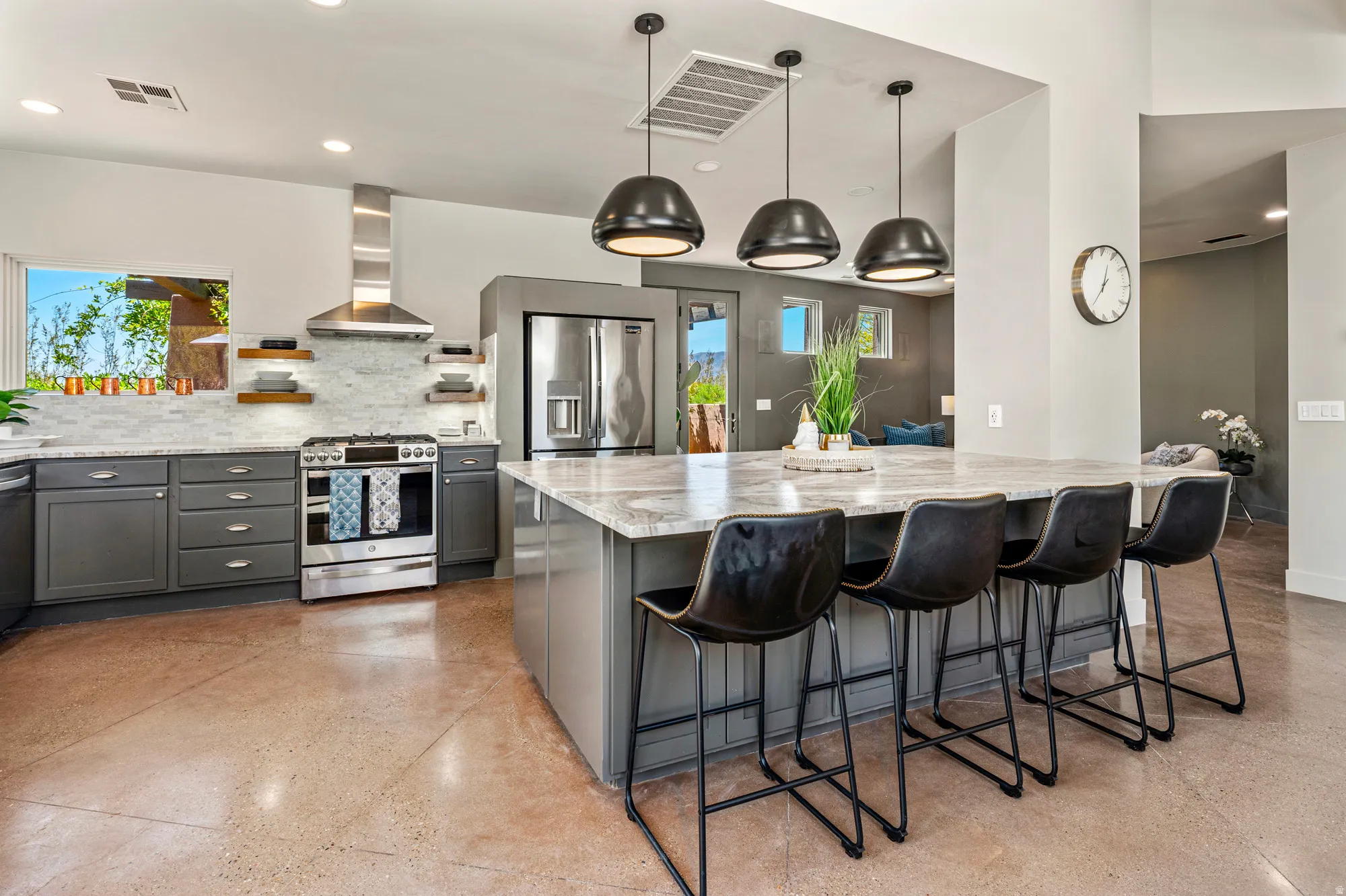 Modern kitchen featuring an expansive center island with seating, stainless steel appliances, and sleek gray cabinetry