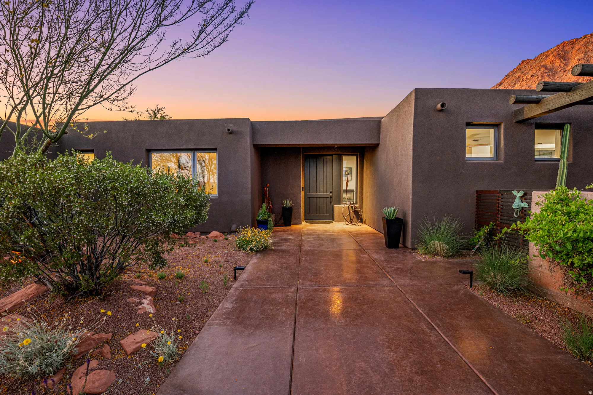 Contemporary stucco exterior with a prominent entry door, surrounded by desert landscaping and a concrete walkway