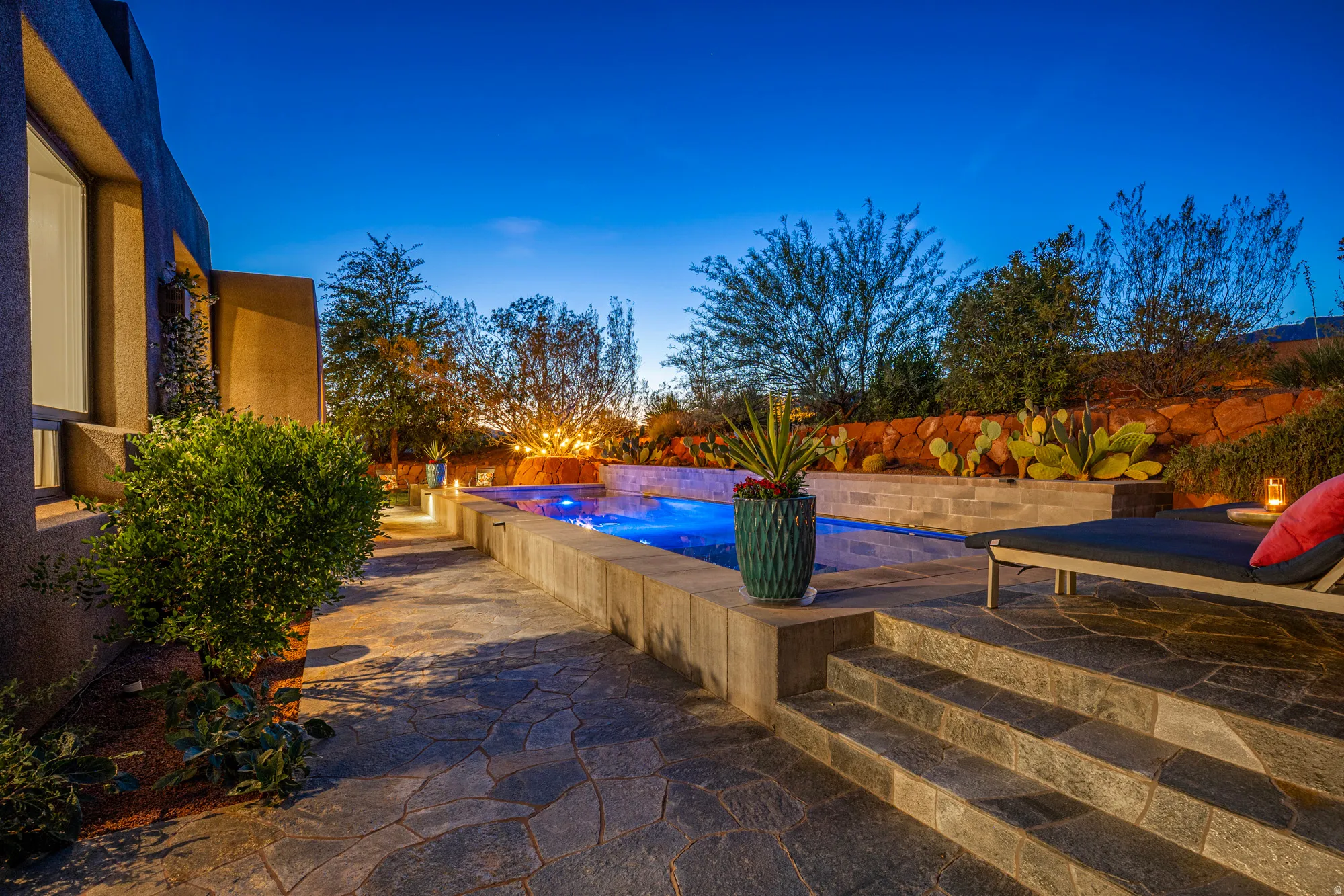 Outdoor living area featuring a custom pool with illuminated water, flagstone patio, and integrated steps