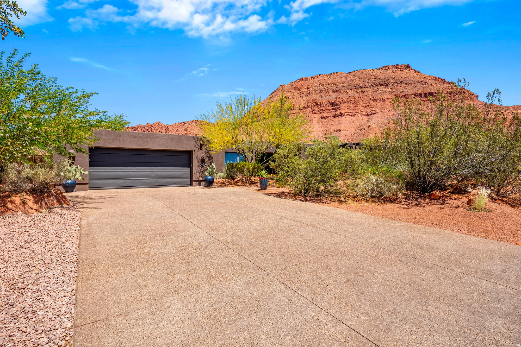 Single-story residence featuring a dark garage door and a concrete driveway