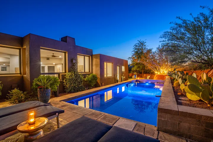 Contemporary exterior featuring a rectangular in-ground swimming pool with integrated lighting, surrounded by stone paver decking