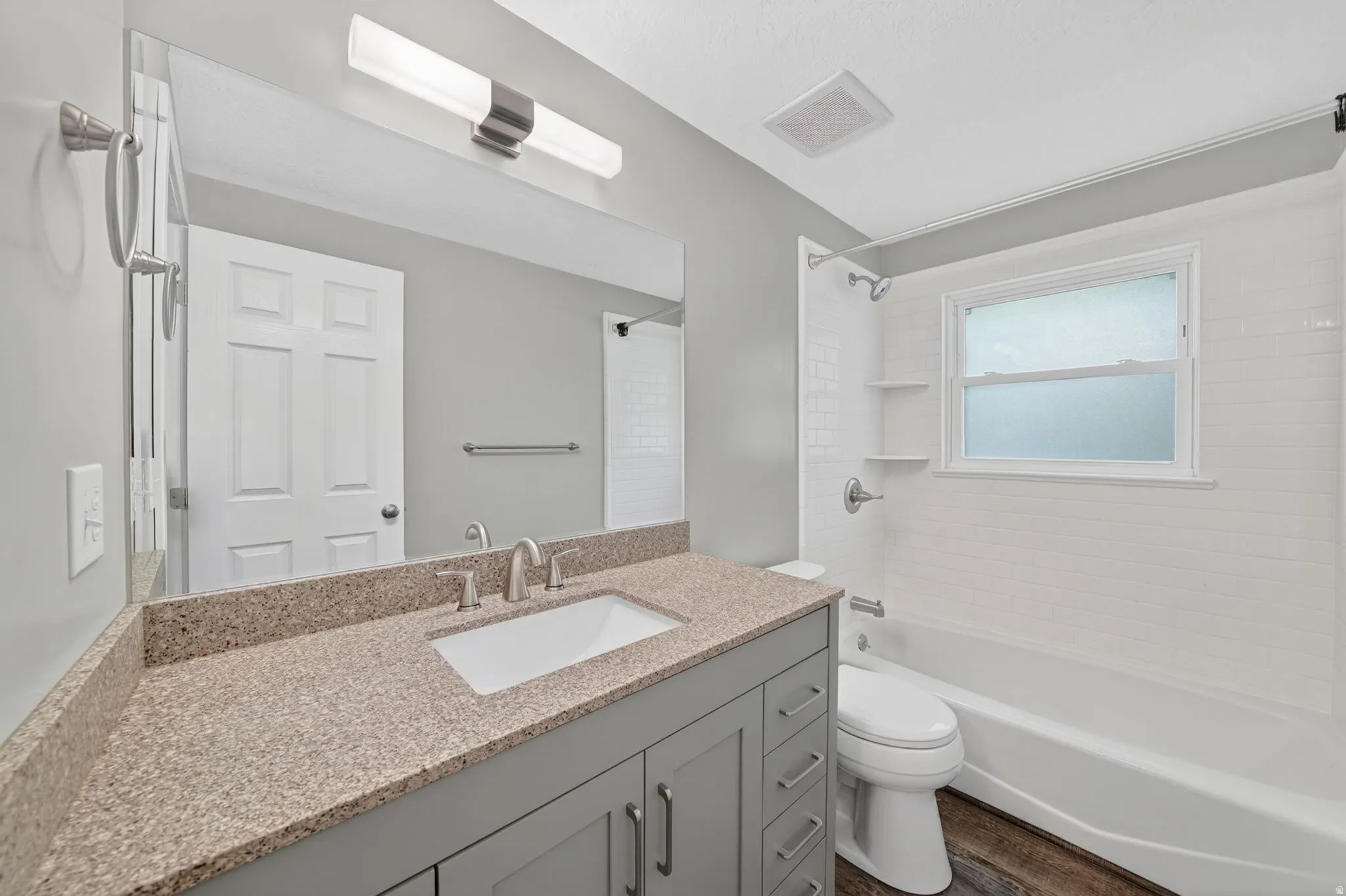 Bathroom with a gray vanity, light speckled countertop, undermount sink, and brushed nickel fixtures