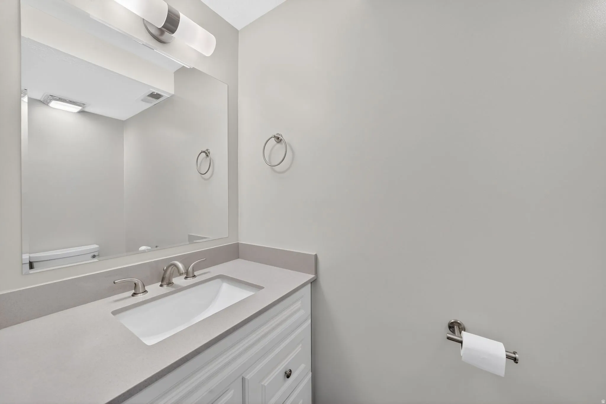 Contemporary vanity featuring a rectangular undermount sink, a light gray countertop, and brushed nickel fixtures