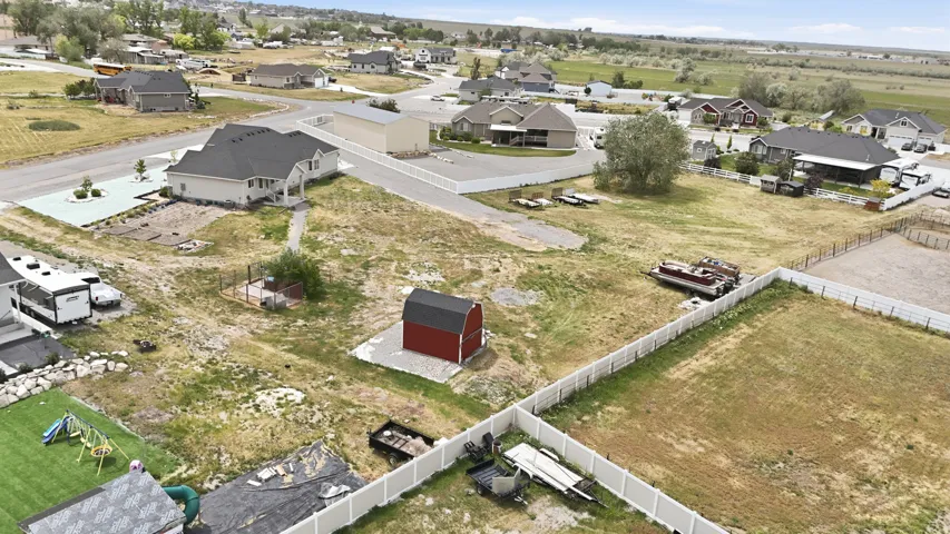 Expansive property featuring a white residence with a dark roof, a detached red barn, and a white picket fence enclosing a portion of the property