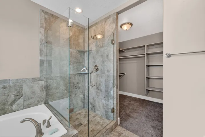 Glass-enclosed shower with stone-look tile surround and built-in shelving