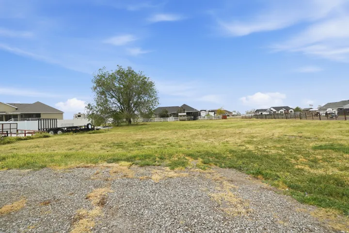 Expansive grassy lot with a gravel foreground and perimeter fencing
