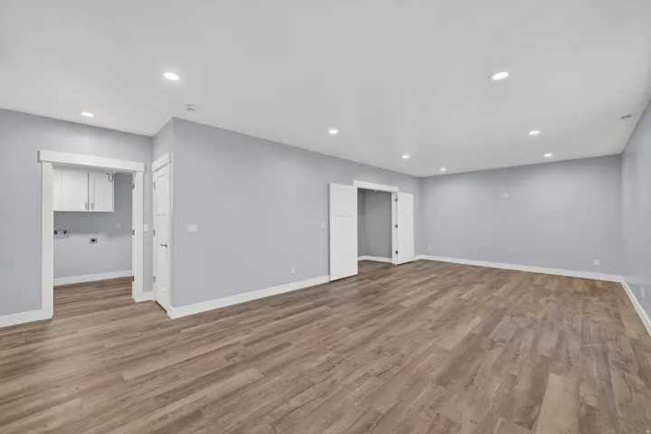 Spacious room featuring wood-finish flooring, recessed lighting, and light blue wall paint