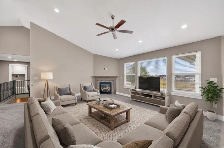 Spacious living area featuring a vaulted ceiling, recessed lighting, and a ceiling fan