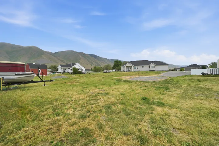 Expansive open lot with natural grass, gravel driveways, and mountain scenery