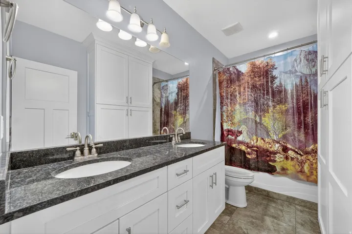 Dual vanity with undermount sinks, a dark stone countertop, and brushed nickel faucets