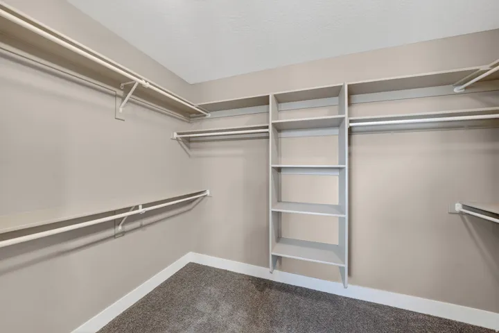 Spacious walk-in closet featuring extensive shelving and hanging rods