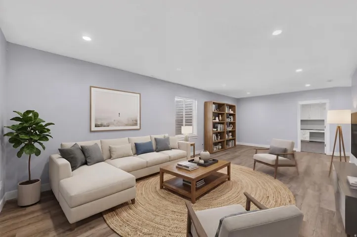 Spacious living area featuring light gray walls, wood-finish flooring, and recessed lighting