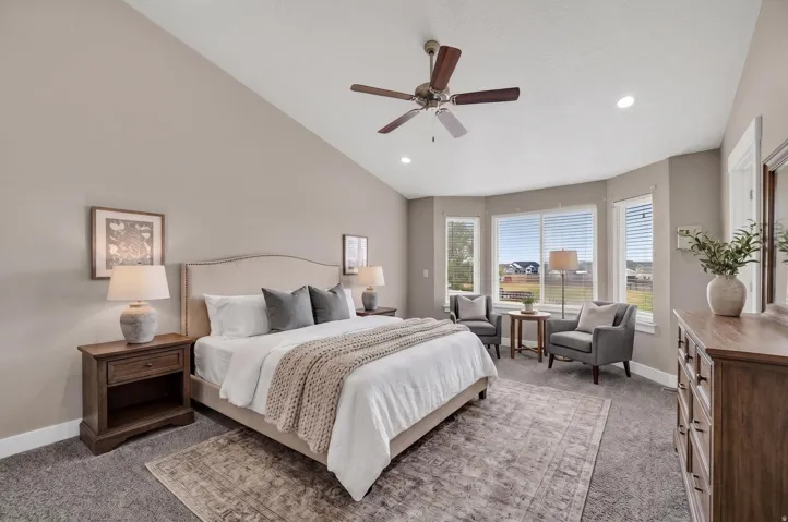 Vaulted ceiling bedroom featuring a ceiling fan, recessed lighting, and a window seat with bay windows