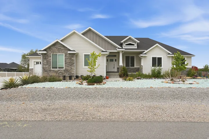 Ranch-style exterior featuring light-colored siding, dark shingle roofing, stone accents, and a front entry porch with columns