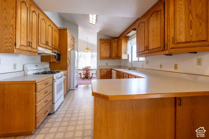 Kitchen featuring wood-finish cabinetry, white countertops, built-in gas range, and a skylight
