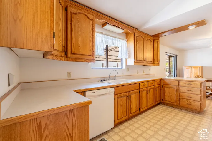 U-shaped kitchen featuring wood cabinetry, white laminate countertops, and a double basin sink
