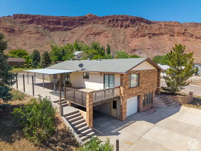Multi-level residence featuring a brick facade, attached garage, and upper-level deck