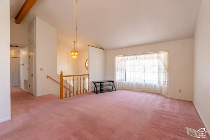 Living area with a large bay window, volume ceiling, and a prominent wood beam