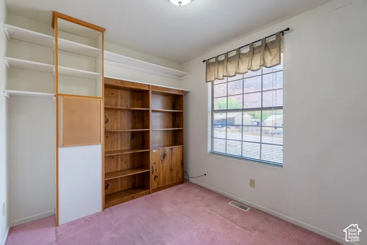 Room featuring built-in wood shelving units and a window with blinds