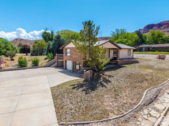 Brick-front home with a split-level design, concrete driveway, and a covered front entry