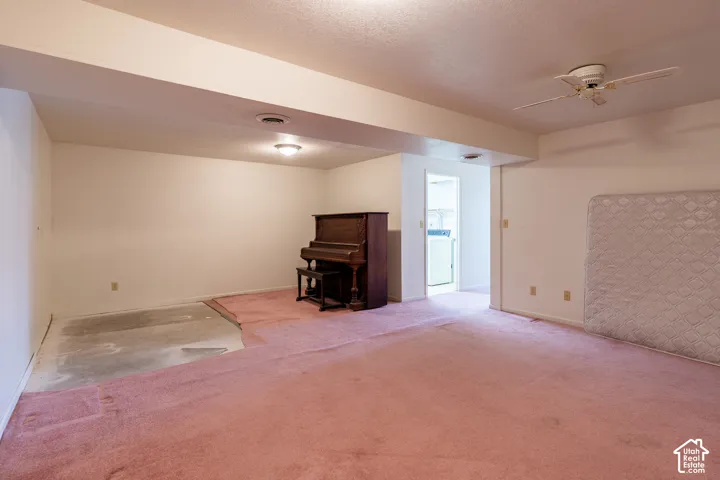 Spacious room with overhead lighting, a ceiling fan, and exposed concrete flooring