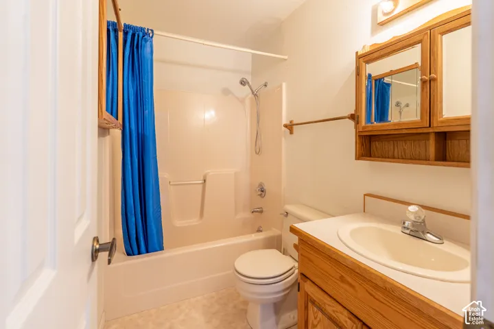 Full bathroom featuring a single vanity with wood-finish cabinetry, a toilet, and a combined shower and bathtub