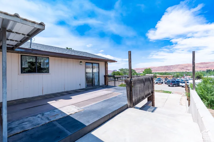 Rear exterior featuring covered patio, sliding glass door, and a concrete stairway