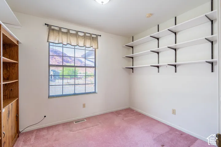 Room featuring a large window with mountain scenery, built-in shelving, wood-finish cabinetry, and neutral wall paint
