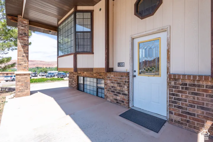Entryway featuring a white door with decorative glass, brick veneer siding, and a large bay window