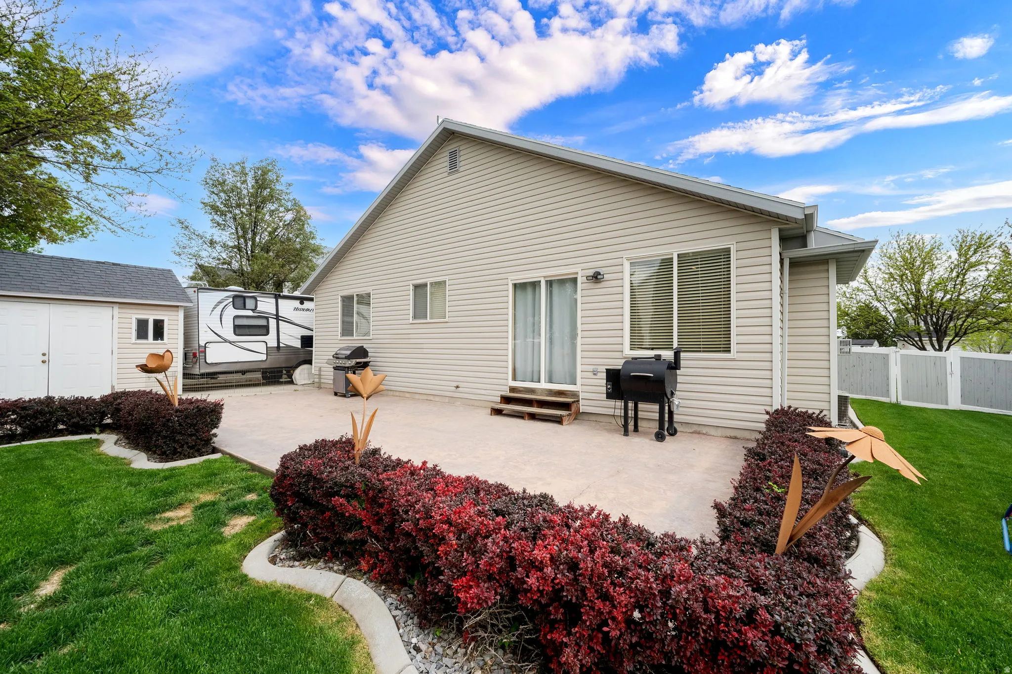 Spacious rear patio with concrete paving and red-leafed shrubs