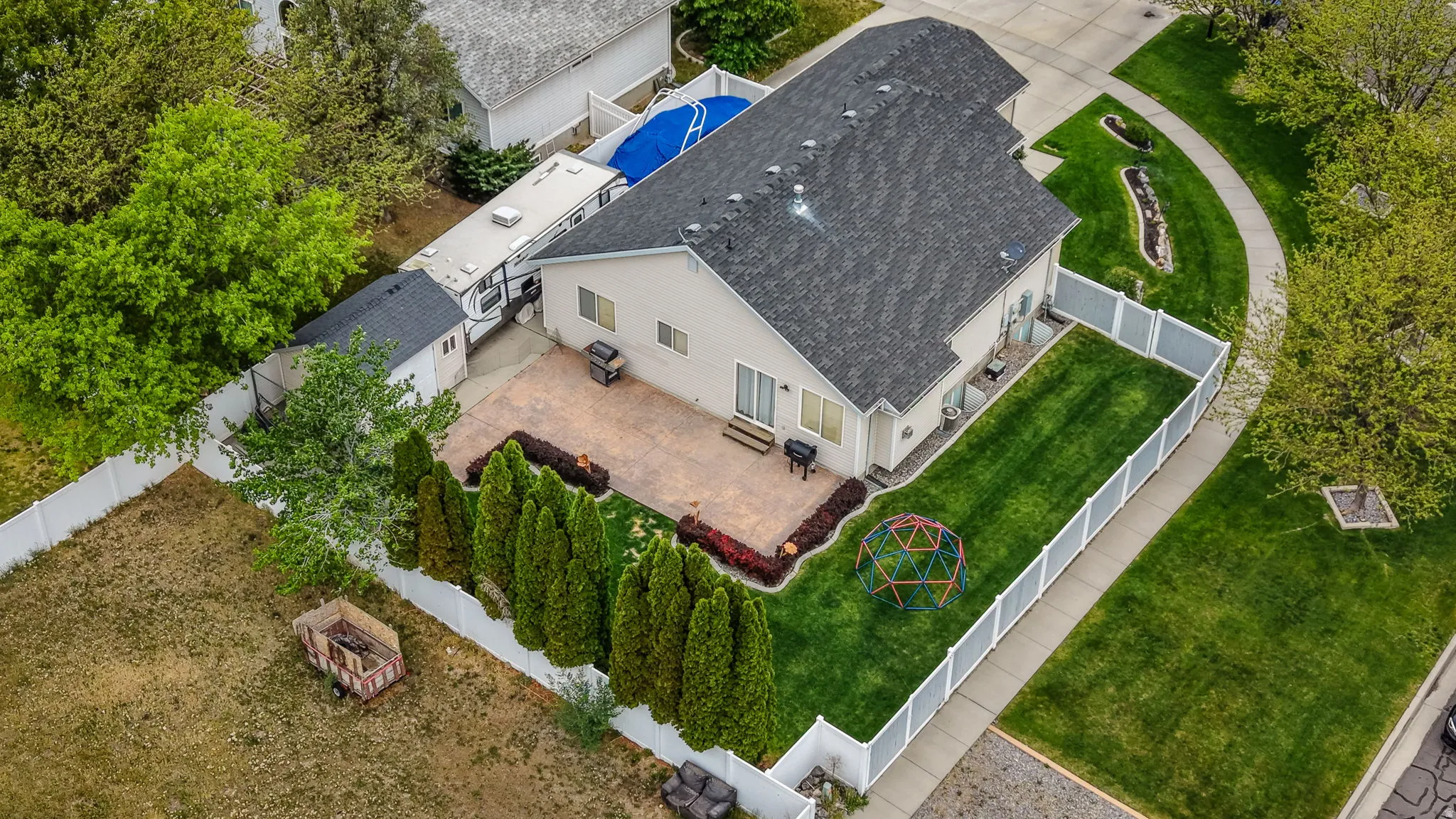 Expansive backyard featuring a patterned paver patio, a manicured lawn, and mature evergreen shrubs