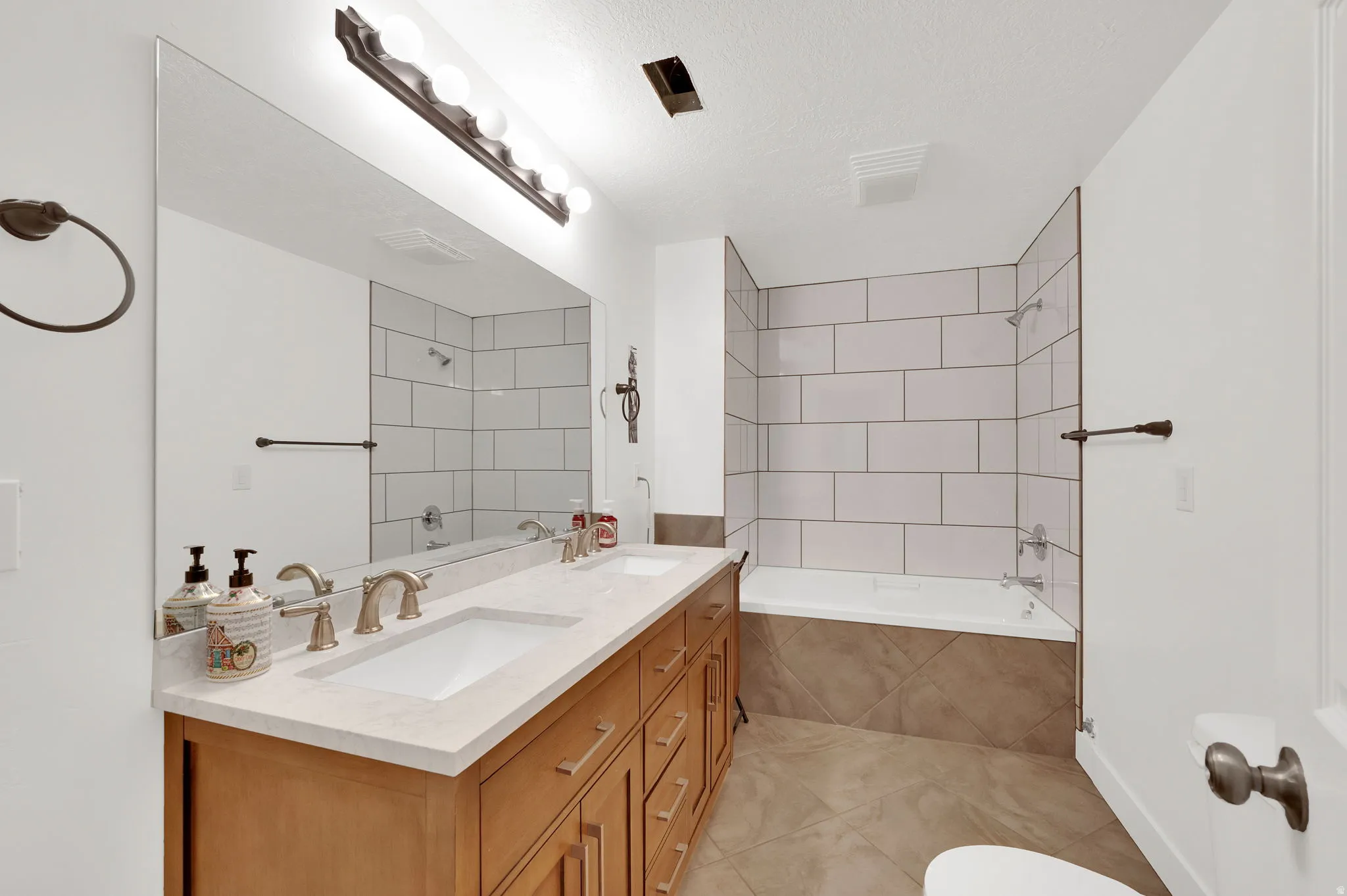 Bathroom featuring a light wood-finish double vanity with integrated sinks and a light-toned countertop