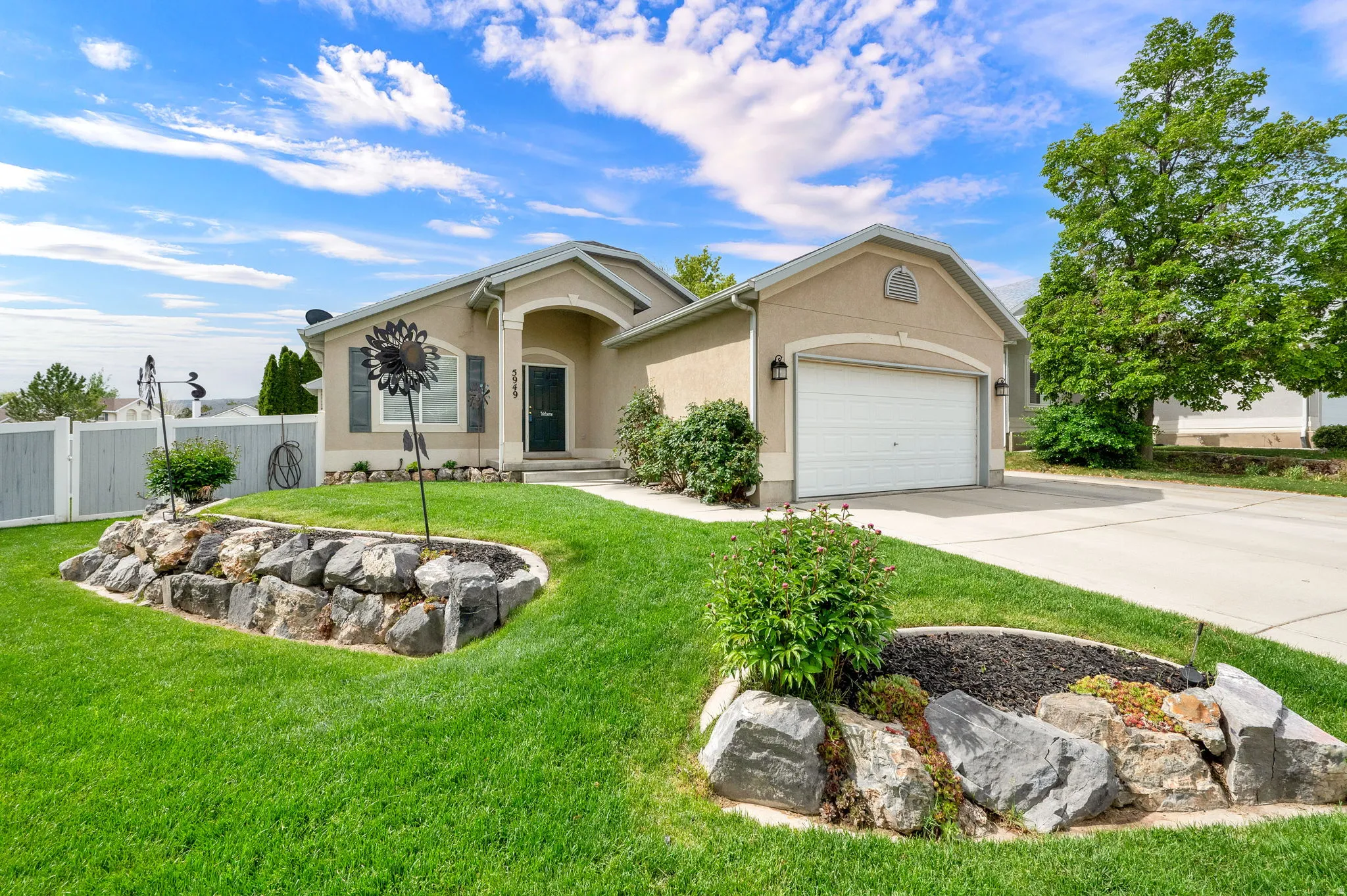 Stucco exterior with an arched entryway, two-car garage, and established landscaping
