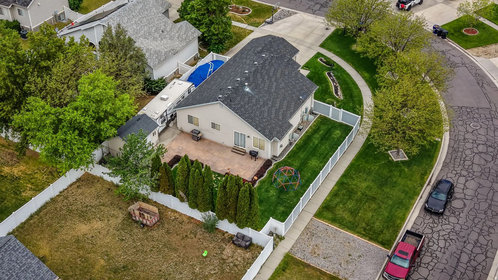 Rear exterior featuring a spacious paver patio, a fenced yard with established landscaping, and a side access area