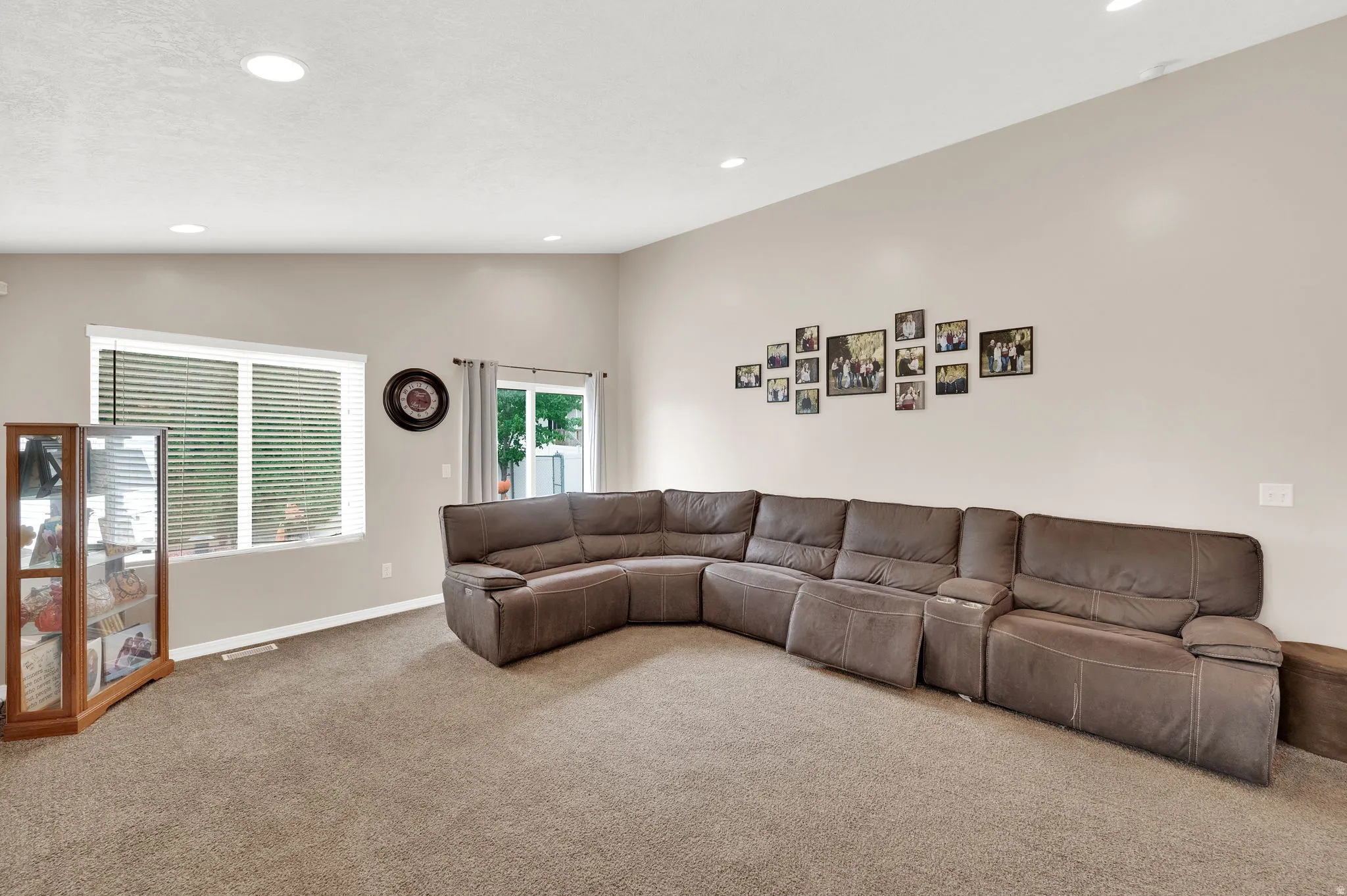 Spacious living area featuring neutral-toned walls, recessed lighting, and soft carpet flooring