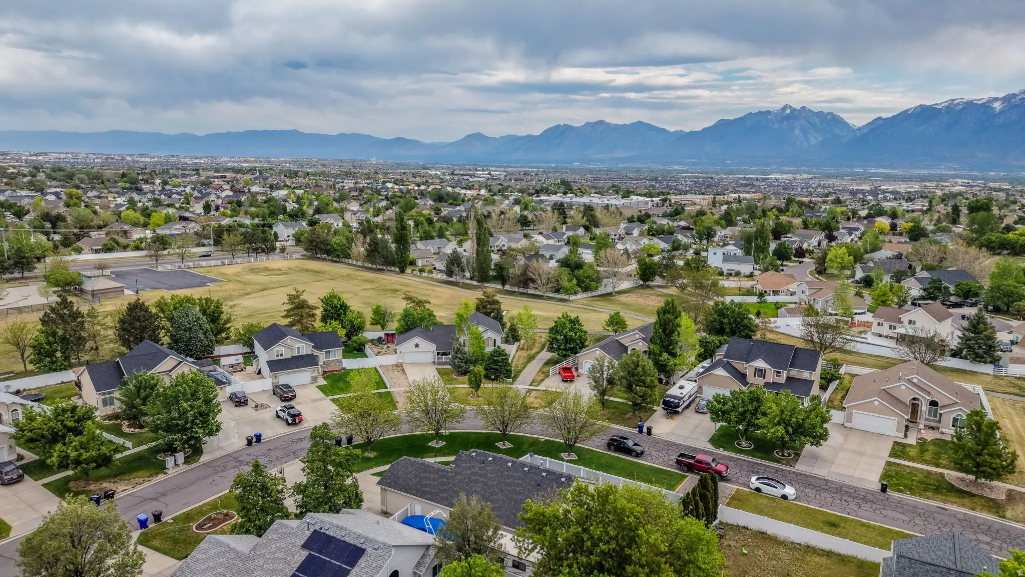 Expansive neighborhood showcasing a mix of single-family homes with mature landscaping, paved streets, and mountain backdrops