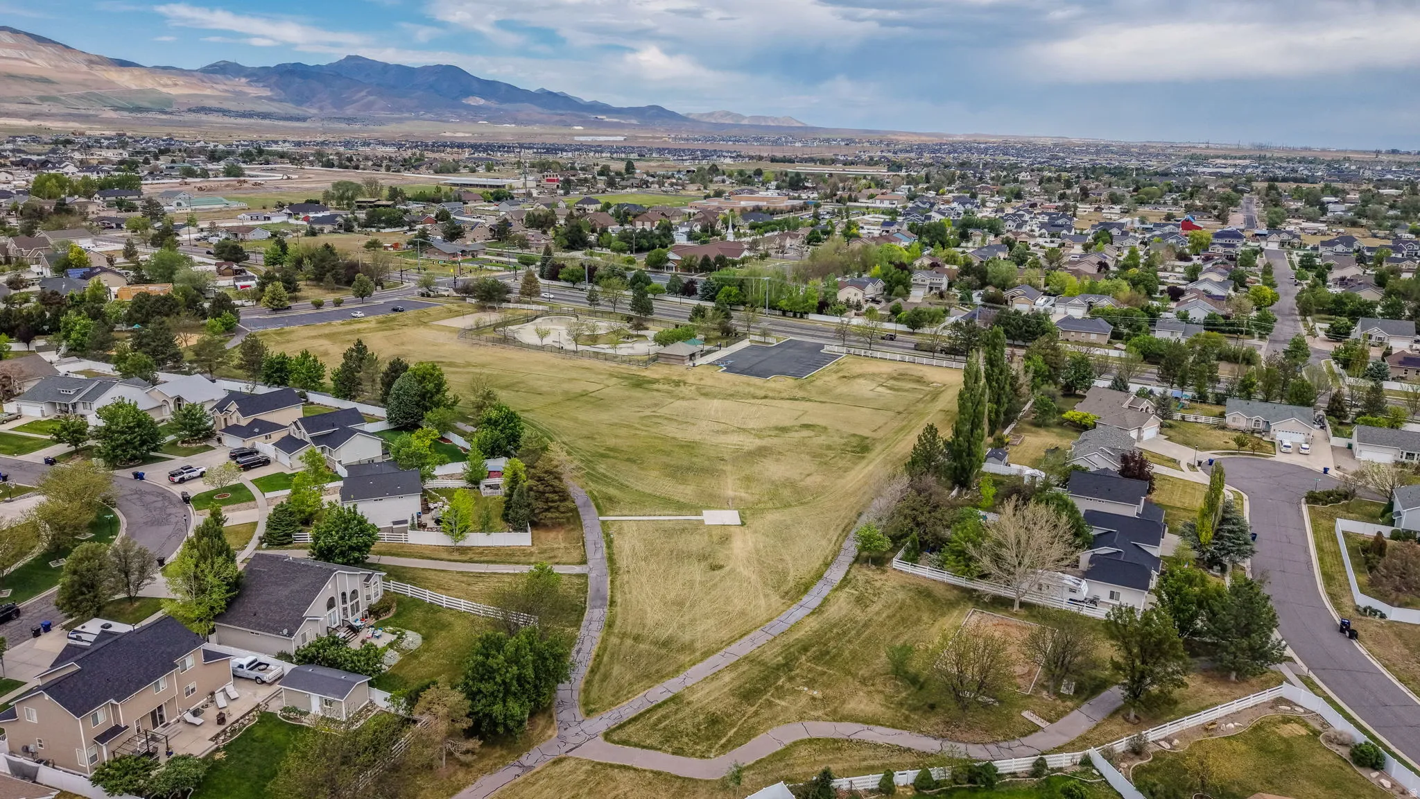 Expansive park area with walking paths, mature trees, and open green space