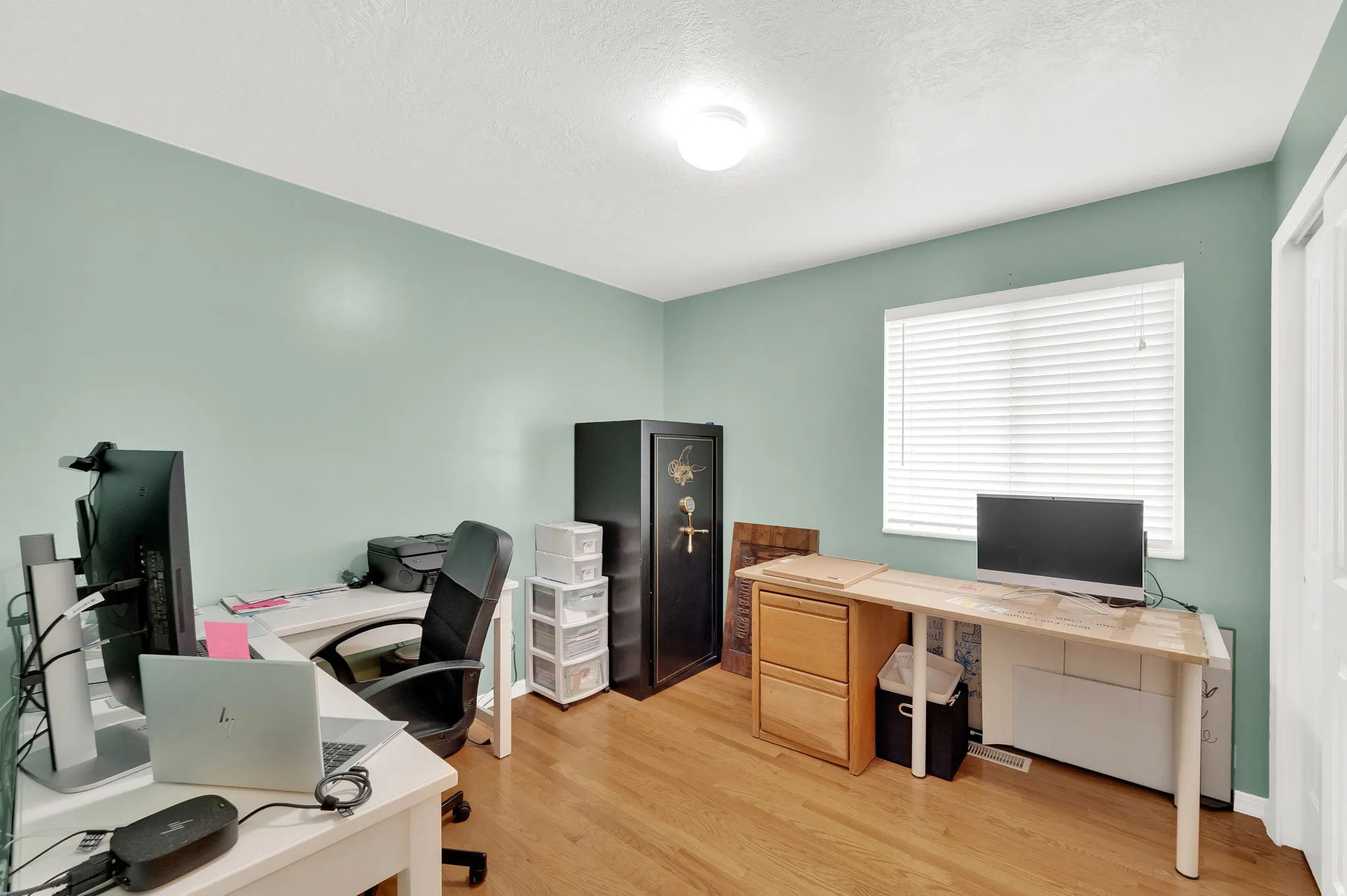 Room featuring wood-finish flooring, a window with horizontal blinds, and a flush mount ceiling light fixture