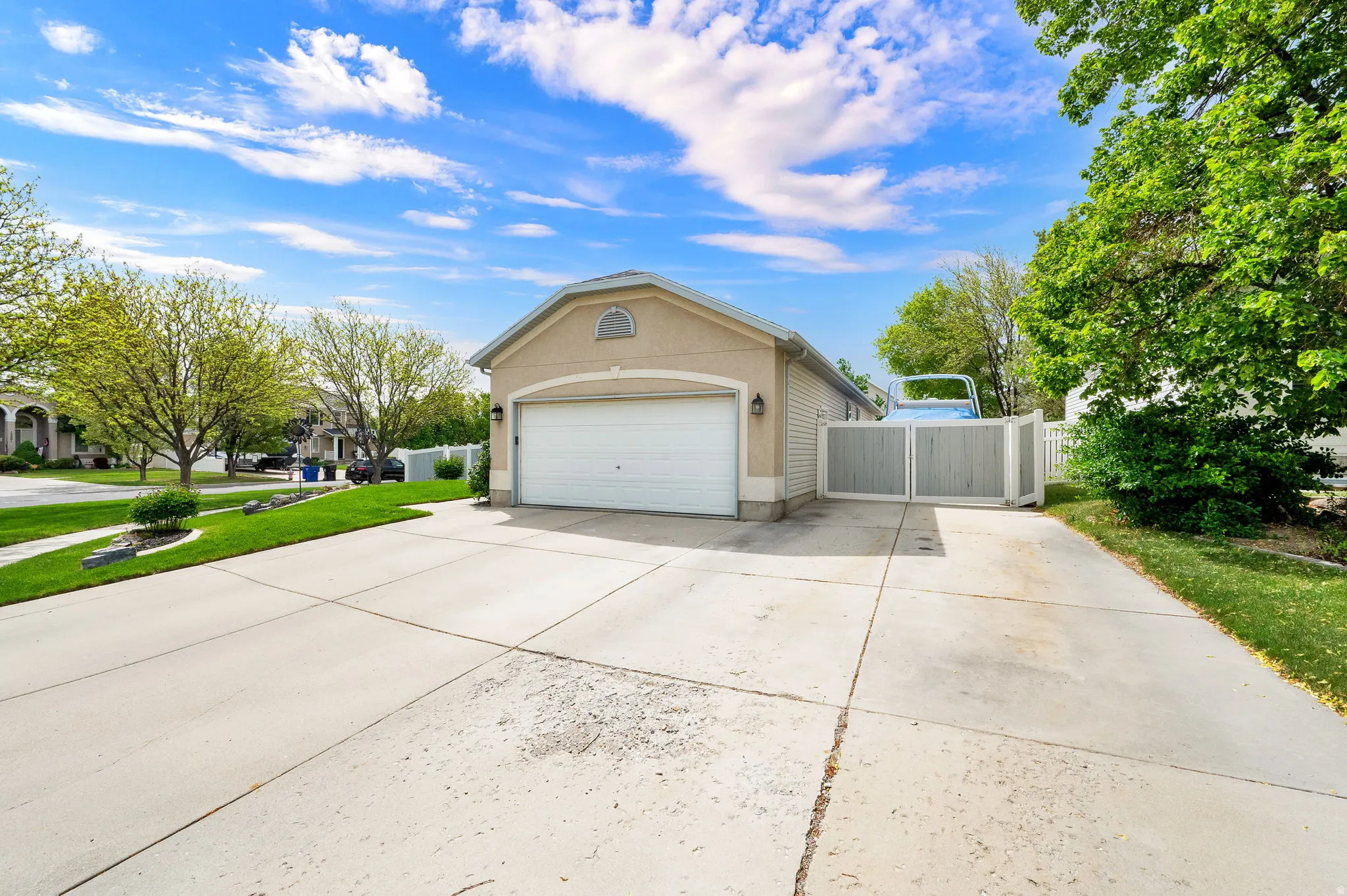 Attached garage with an arched transom window, a concrete driveway, and a side gate featuring vertical wood paneling