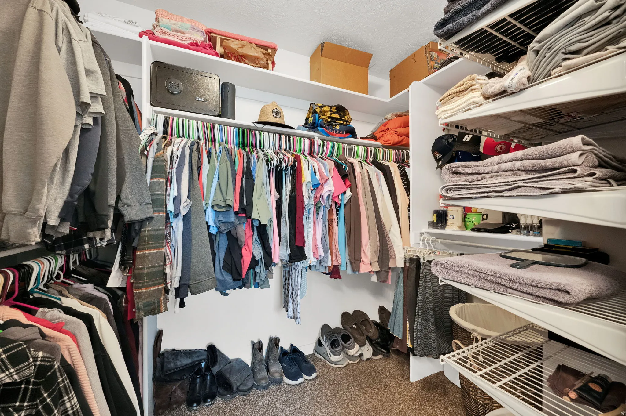Walk-in closet featuring white built-in shelving, multiple hanging rods, and carpet flooring