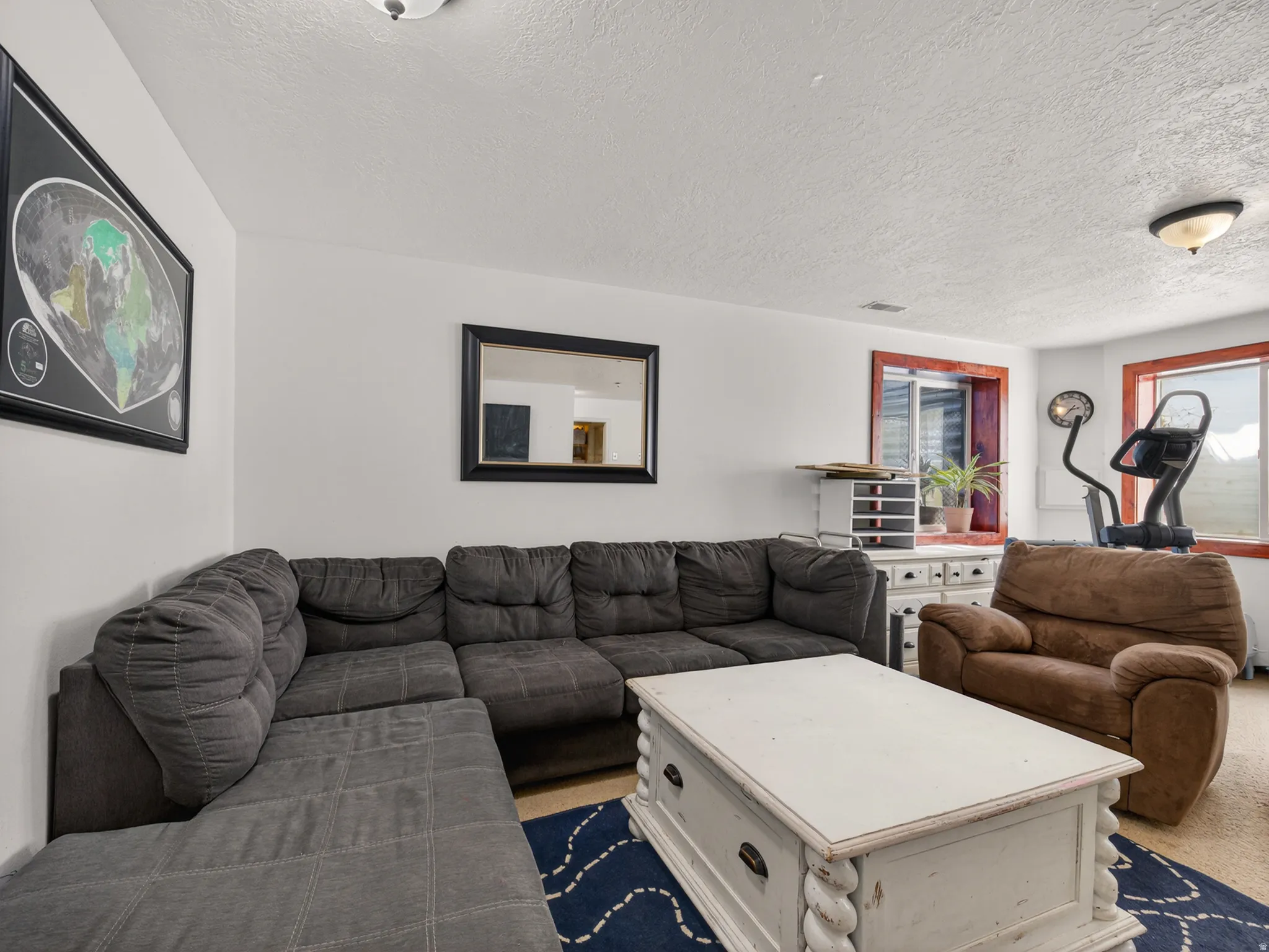 Basement family room featuring white walls and a textured ceiling